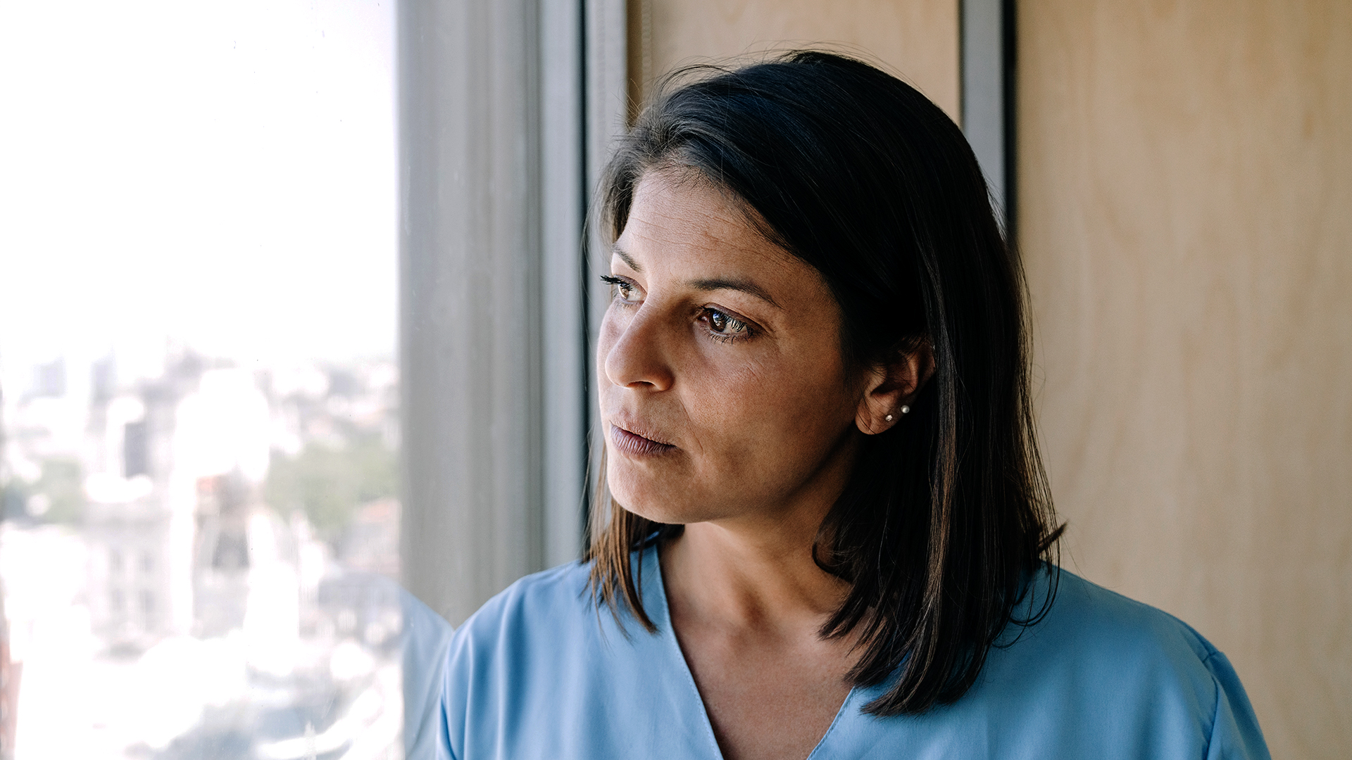 Enfermera pensativa, mira por la ventana de un centro sanitario
